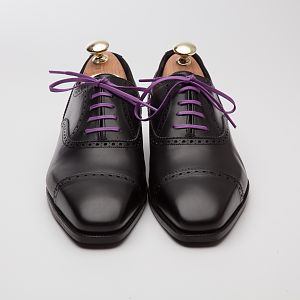 Photograph of our Alfred Sargent black oxford shoes with a pair of purple laces. These purple shoe laces really pop on the black shoes and make what would otherwise be a very traditional work shoe much more casual.