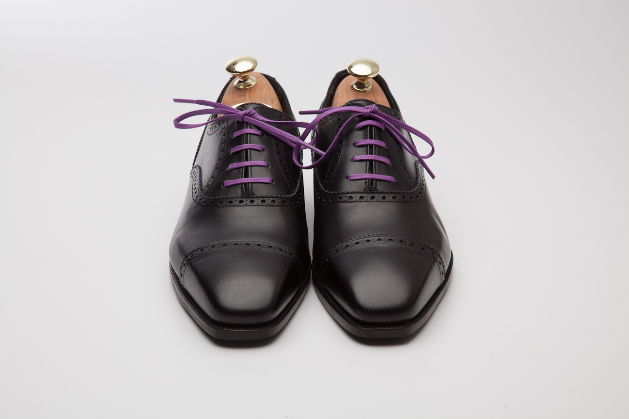 Photograph of our Alfred Sargent black oxford shoes with a pair of purple laces. These purple shoe laces really pop on the black shoes and make what would otherwise be a very traditional work shoe much more casual.